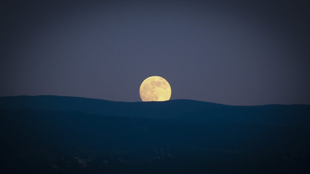 moon behind mountain in lake garda